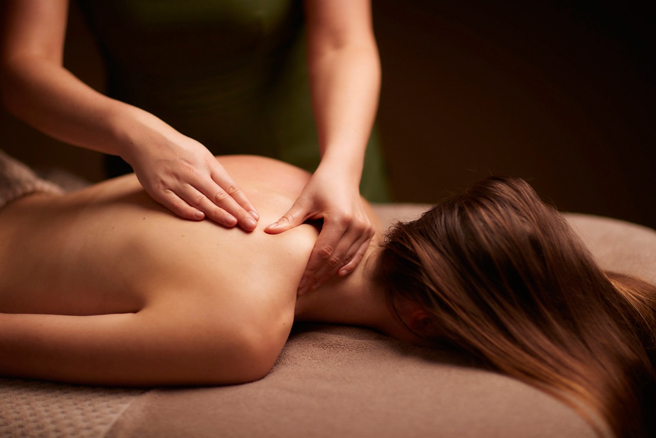 Spa therapist giving a woman a relaxing back massage body treatment.